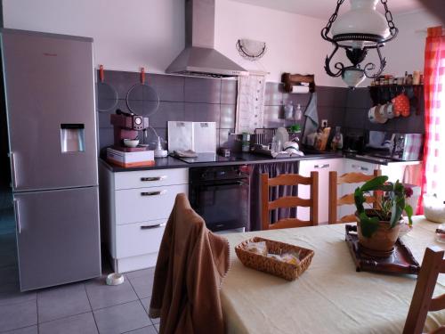 une cuisine avec une table et un réfrigérateur dans l'établissement Chez Cathy, à Saint-Julien-en-Born