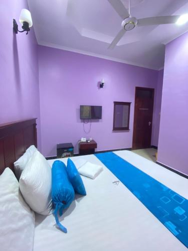 a bedroom with a large bed with blue pillows at Makidonia Lodge in Dar es Salaam