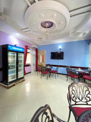una sala da pranzo con tavoli, sedie e TV di Makidonia Lodge a Dar es Salaam