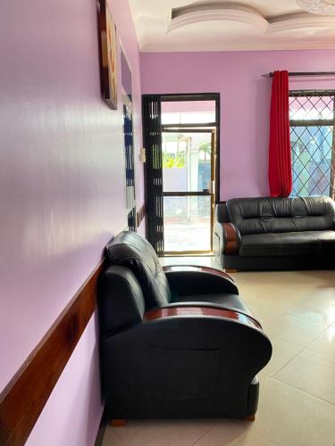 - un salon avec des meubles en cuir noir et des murs roses dans l'établissement Makidonia Lodge, à Dar es Salaam
