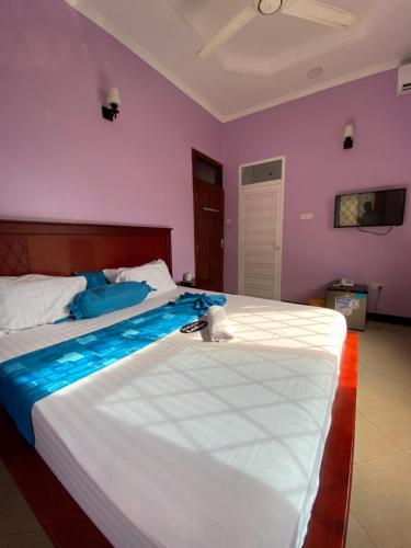 1 Schlafzimmer mit 2 Betten und lila Wänden in der Unterkunft Makidonia Lodge in Daressalam