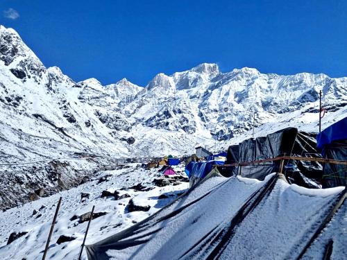 una montaña cubierta de nieve con un grupo de tiendas de campaña en Rajwan peradise tents, en Kedārnāth