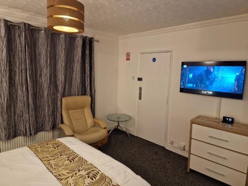 a hotel room with a bed and a chair and a tv at Steyn Guest Lodge in Buckinghamshire