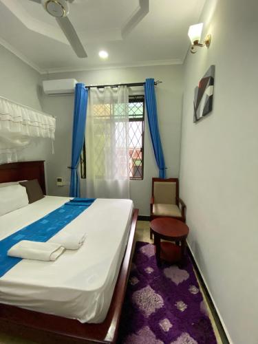 a bedroom with a bed and a chair and a window at Magdon Lodge in Dar es Salaam