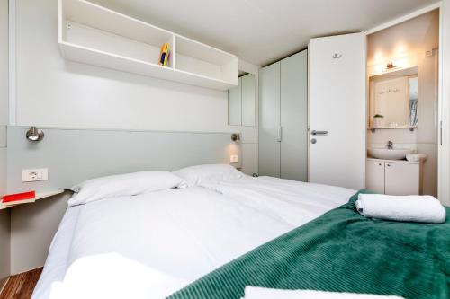 a bedroom with a large white bed with a green blanket at Glamping and Mobile Homes Lavanda - Holiday Centre Bi VIllage in Fažana