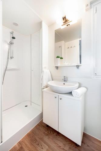 a white bathroom with a sink and a shower at Glamping and Mobile Homes Lavanda - Holiday Centre Bi VIllage in Fažana