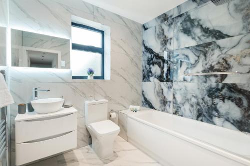 a bathroom with a white tub and a toilet and a sink at Cozy Two Bedrooms Flat in Coulsdon, CR5 in Coulsdon