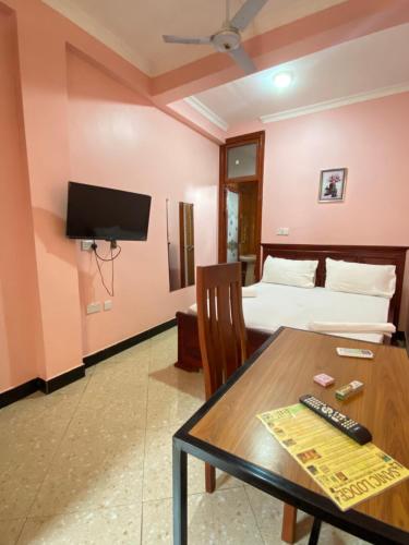 a room with a table and a bed and a television at Sanic Lodge in Dar es Salaam