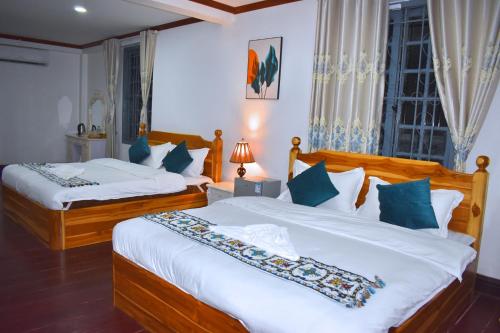 1 dormitorio con 2 camas y ventana en Monsane villa, en Luang Prabang