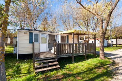 a tiny house with a porch and a deck at Glamping and Mobile Homes Lavanda - Holiday Centre Bi VIllage in Fažana