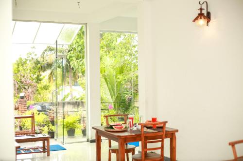 ein Esszimmer mit einem Tisch und einem großen Fenster in der Unterkunft The Blue Haze Weligama in Weligama