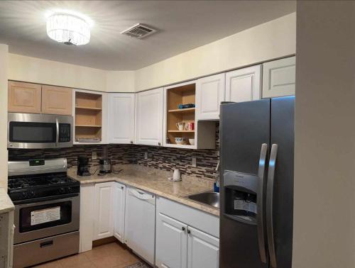a kitchen with white cabinets and a stainless steel refrigerator at Room J Divine Villa and Resorts 5mins to EWR Airport and 4mins to Penn Station Newark, New York in Newark
