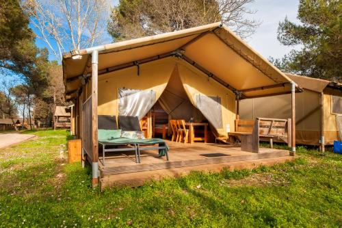 a tent with a table and chairs in a field at Glamping and Mobile Homes Lavanda - Holiday Centre Bi VIllage in Fažana