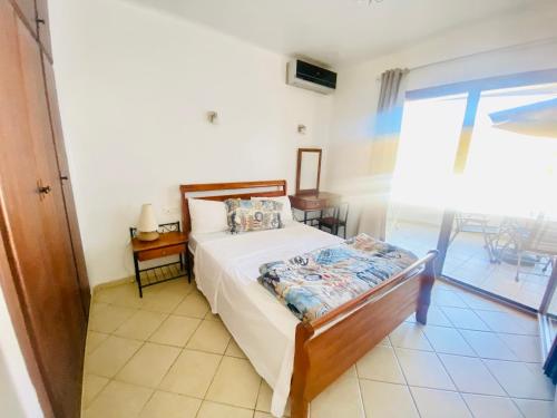 a bedroom with a bed and a table and a window at Cabo Dream Apparthotel in Cabo Negro