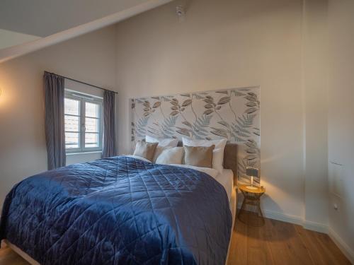 a bedroom with a bed with a blue comforter and a window at Alte Bäckerei Königstein Aparthotel und Café in Königstein an der Elbe