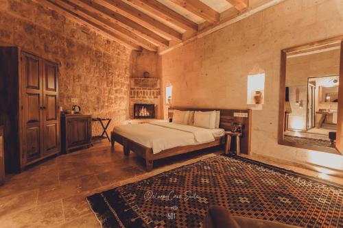 Nino Cave Suites في أوروغوب: غرفة نوم بسرير في غرفة بها موقد