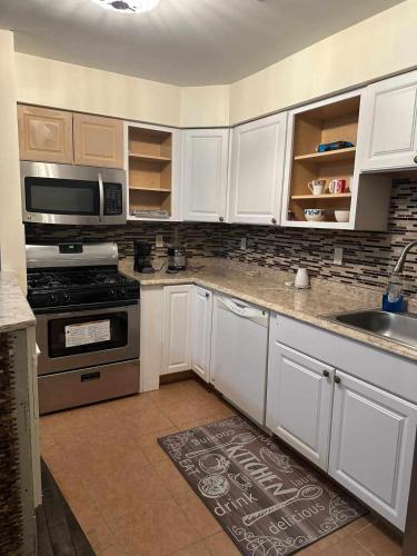 a kitchen with white cabinets and a stove top oven at Room K Divine Villa and Resorts 5mins to EWR Airport and 4mins to Penn Station Newark, New York in Newark
