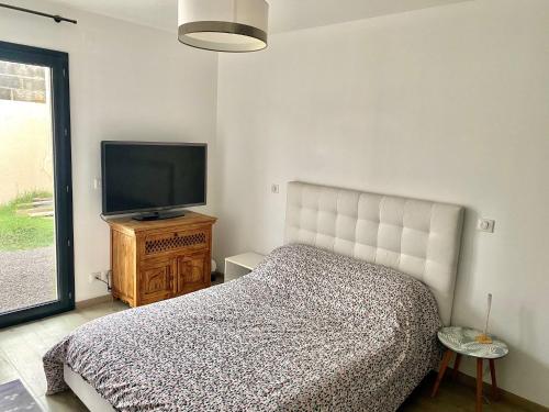 une chambre avec un lit et une télévision à écran plat dans l'établissement Villa de 100m² climatisée sur Mèze, à Mèze