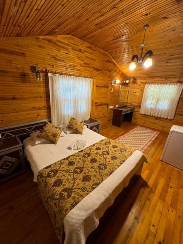a bedroom with a bed in a wooden room at Hotel Yavuz Bungalow in Cıralı