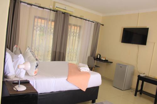 um quarto de hotel com uma cama e uma televisão em Kunzi B&B em Gaborone