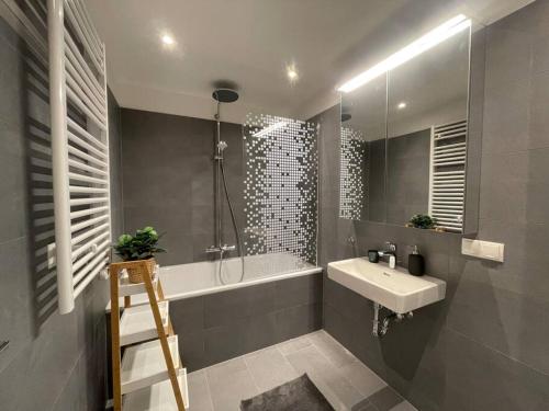 ein Badezimmer mit einem Waschbecken, einer Badewanne und einer Dusche in der Unterkunft Modern Rooftop Apartment with Free Parking in Wien