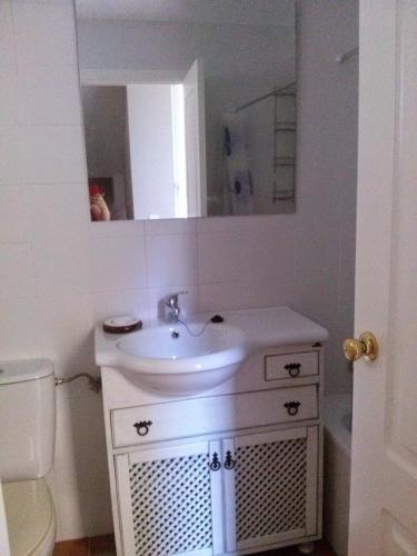 a white bathroom with a sink and a mirror at Casa Tartessos in Costa Ballena