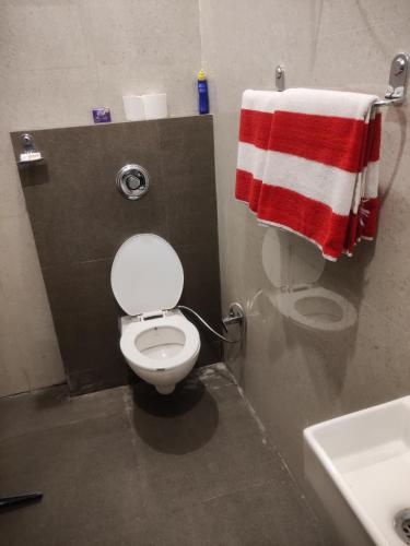 a bathroom with a toilet and a red and white towel at Zuhause apartment in Amritsar