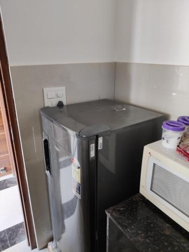 a small refrigerator in a kitchen next to a microwave at Zuhause apartment in Amritsar