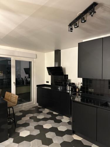une cuisine avec des armoires noires et un sol en damier dans l'établissement Très bel appartement de 4 pièces, à Saint-Ouen