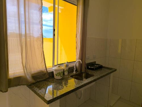 um balcão de casa de banho com um lavatório e uma janela em Pousada Peruíbe Frente ao Mar - Suítes Gourmet em Peruíbe