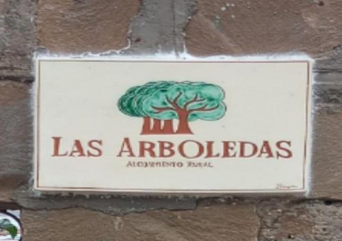 een bord op een stenen muur met een boom erop bij Las Arboledas alojamiento rural in Baeza