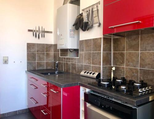 La cuisine est équipée de placards rouges et d'un four avec plaques de cuisson. dans l'établissement Spacieux et confort, entre Vieux-port et Pharo, à Marseille