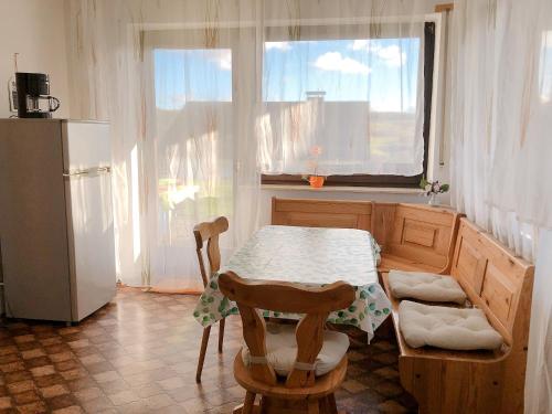 eine Küche mit einem Tisch, einem Kühlschrank und einem Fenster in der Unterkunft Ferienwohnung auf dem Bünberg in Bebra