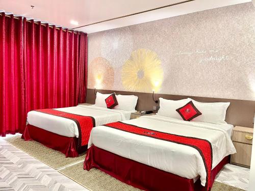 two beds in a hotel room with red curtains at B.O.B Hotel in Cao Lãnh