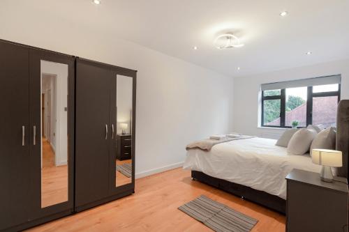 a bedroom with a large bed and a mirror at Modern Comfort Two Bedrooms Flat, Coulsdon CR5 in Coulsdon