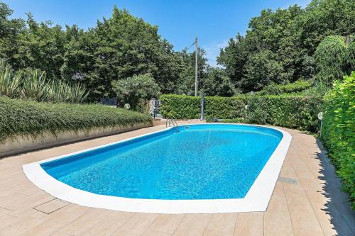 une piscine bleue dans une cour arborée dans l'établissement Keplero - Einzigartiges Appartement mit traumhaften Ausblick, à Soiano del Lago