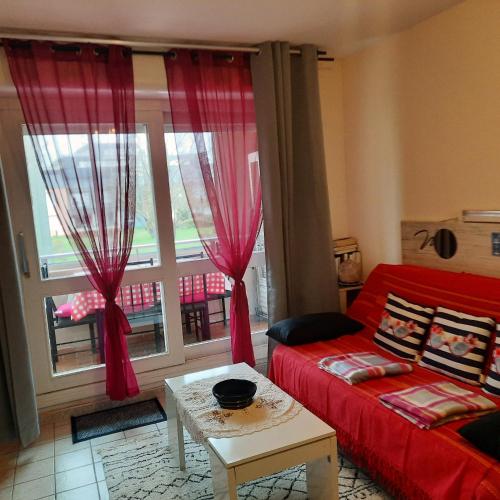 - un salon avec un canapé rouge et une fenêtre dans l'établissement PLAGE et LA MER TRES PROCHE, à Courseulles-sur-Mer