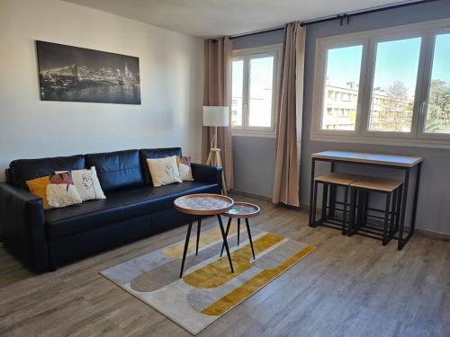 een woonkamer met een zwarte bank en een tafel bij Appartement Art deco proche bords de Marne in Neuilly-sur-Marne