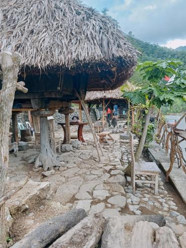 uma cabana com telhado de palha e um caminho de pedra em Agamang Traditional House Inn em Banaue
