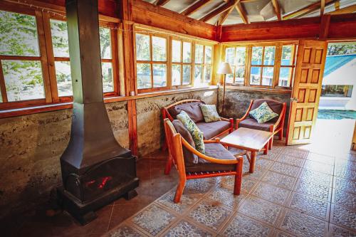 a living room with a fireplace and chairs and a stove at Vista al volcán con tinaja y río en Conguillío in Curacautín