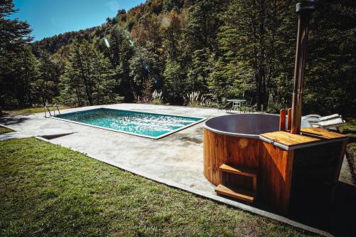 a swimming pool with a wooden tub in the grass at Vista al volcán con tinaja y río en Conguillío in Curacautín