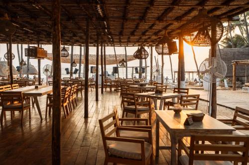 an empty restaurant with wooden tables and chairs at Thalassa Beach Boutique Resort in Goa Velha