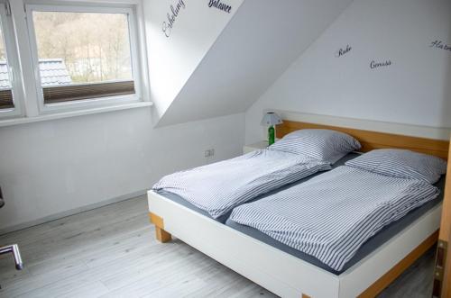 a bed in a white room with a window at Ferienwohnung 1 in Wilhelmsfeld