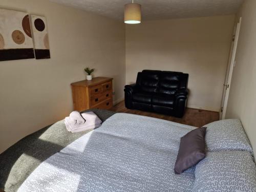 a bedroom with a bed and a black leather chair at Beaumont Court in Coventry