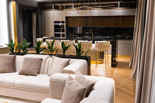 a living room with white couches and a kitchen at Deluxe Aparthotel MARWELL RESIDENCE in Suceava