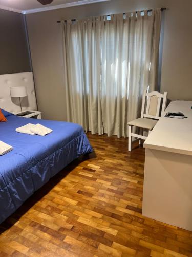 a room with a bed and a chair and a window at Garden House Hotel in Río Cuarto