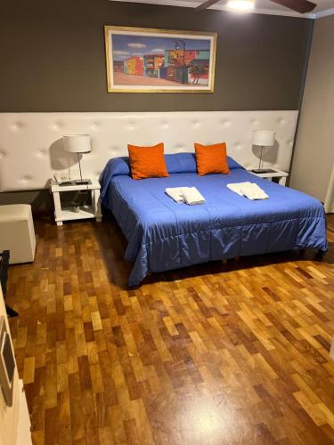 1 dormitorio con 1 cama con sábanas azules y almohadas de color naranja en Garden House Hotel en Río Cuarto