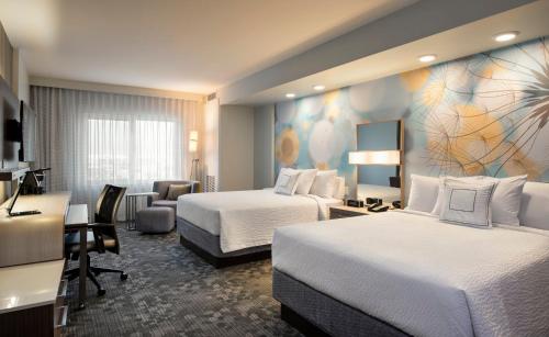 a hotel room with two beds and a desk at Courtyard by Marriott Calgary South in Calgary