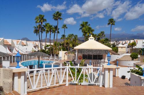 vista sulla piscina di un resort con palme di The Palms Golf Del Sur - Casa Andromeda a San Miguel de Abona