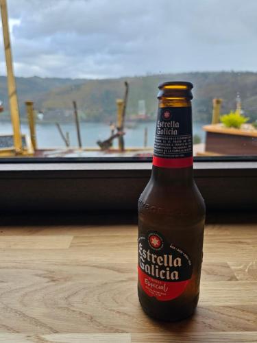 a bottle of beer sitting on a table in front of a window at Viña Candaz By Oktheway in Taboada